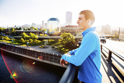 Thoughtful man looking away while standing on footpath against clear sky