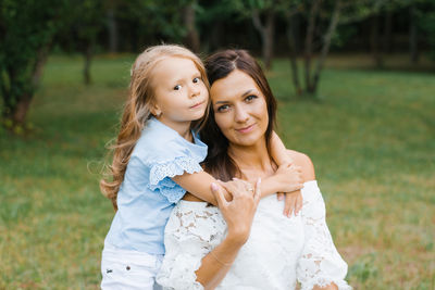 Five-year-old daughter hugs her mother's neck