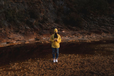 Young lady in yellow raincoat strolling in nature