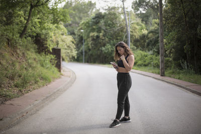 Full length of woman on road against trees