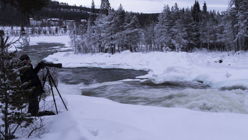 Frozen river by trees during winter