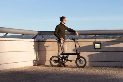 Young man using a folding electric bicycle to move in the city where he lives 