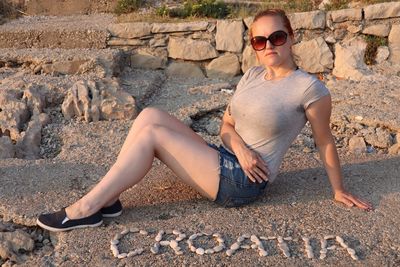 Full length portrait of young woman sitting outdoors