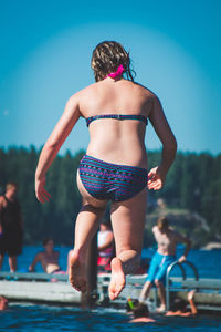 Rear view of woman jumping in swimming pool