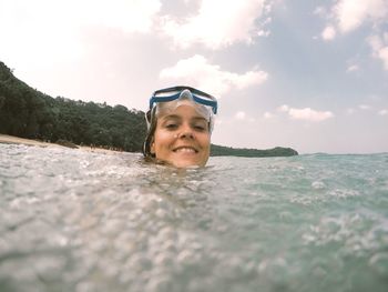 Portrait of smiling man swimming in sea against sky