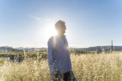 Senior man standing on a field at sunset