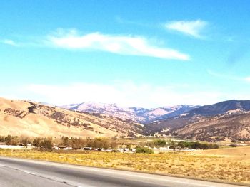 Road by mountains against blue sky