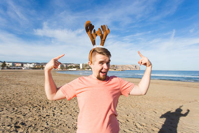 Portrait of friends standing on beach against sky