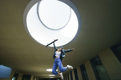 Young woman jumping under skylight