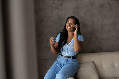Young black woman working at home with smartphone on her couch in the living room. home office 