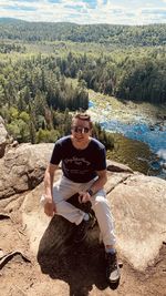 Portrait of young man sitting on rock