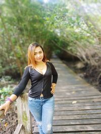 Portrait of smiling young woman standing against trees