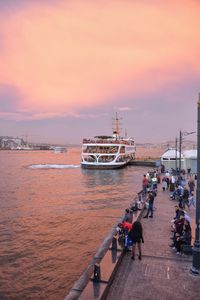 People on boat at sea against sky during sunset