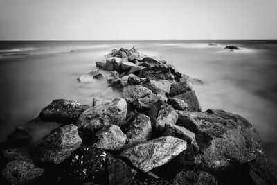 Scenic view of rocks by sea against sky