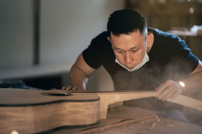 Man working over guitar on table