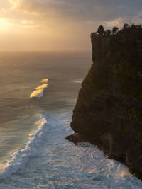 Rocks in sea against sky during sunset