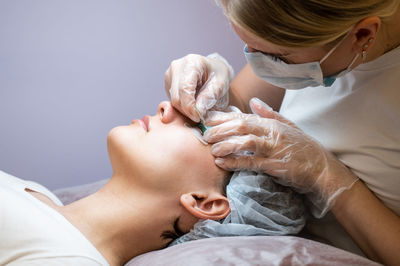 Young woman undergoing eyelash tinting and lamination procedure.