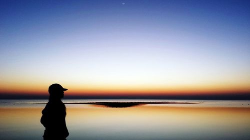 Silhouette woman standing on beach against clear sky
