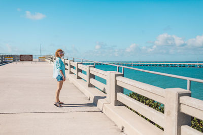 Rear view of woman walking on beach against clear sky