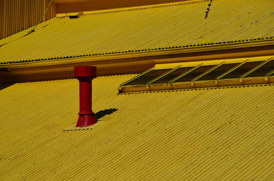 Low angle view of metallic roof against yellow wall