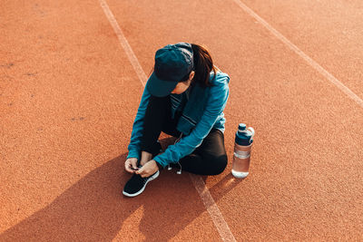 High angle view of woman tying shoelace on sports track