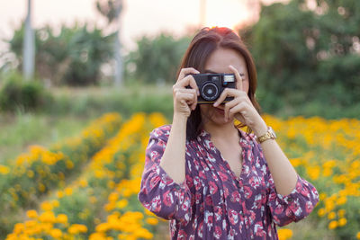 Young woman photographing with camera on field