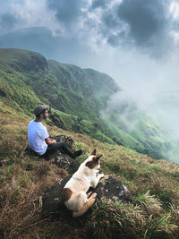 Man lying on mountain against sky