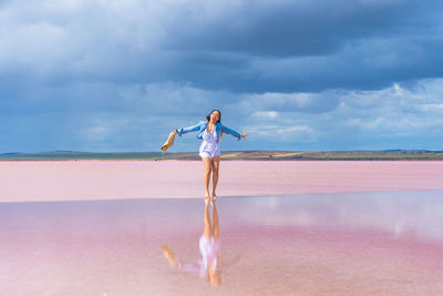 Full length of woman standing at beach against sky