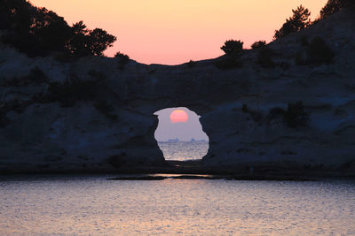 Silhouette mountain by sea against sky during sunset