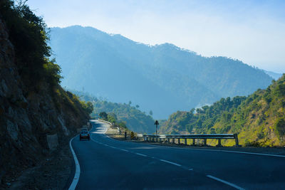 Road by mountains against sky