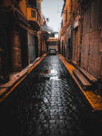 Surface level of wet street amidst buildings in city