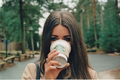 Close-up portrait of woman holding camera in park