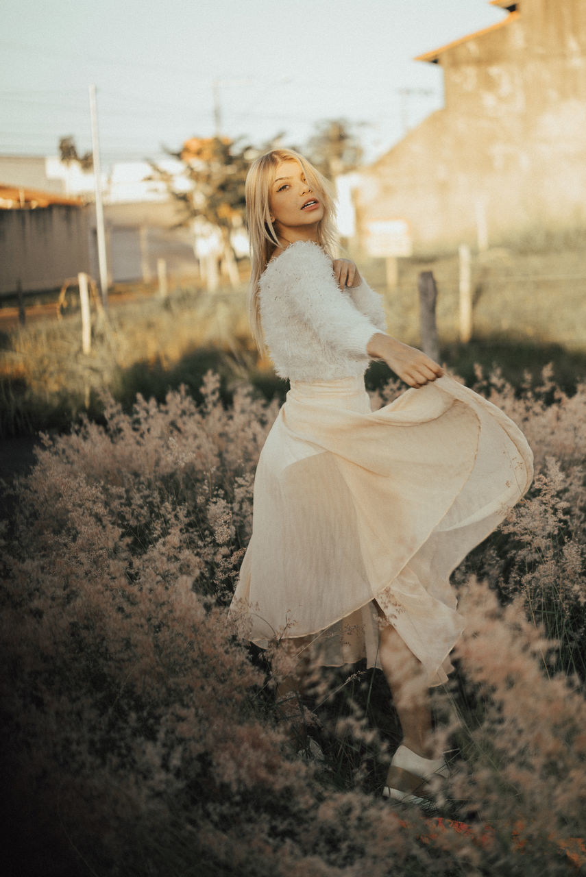 one person, women, blond hair, young adult, full length, hair, young women, real people, looking at camera, fashion, leisure activity, land, clothing, lifestyles, portrait, field, females, beautiful woman, hairstyle, outdoors