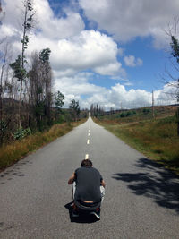 Rear view of man sitting on road