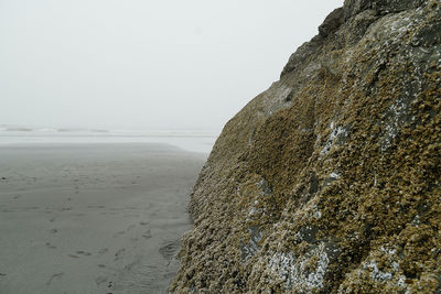 Rock formation on beach against clear sky