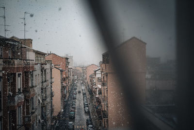 Buildings seen through wet glass window during rainy season