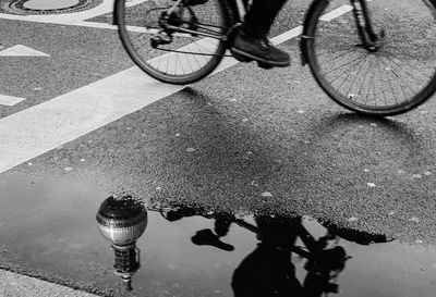 Low section of man with bicycle on puddle