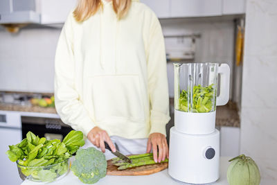 Midsection of woman standing in kitchen at home