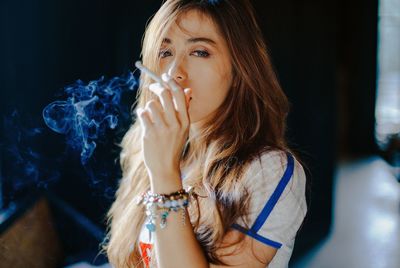 Portrait of young woman smoking cigarette at night