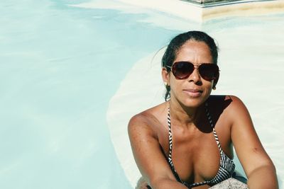 High angle portrait of woman wearing sunglasses in swimming pool