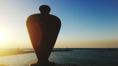 Silhouette man standing by sea against clear sky during sunset