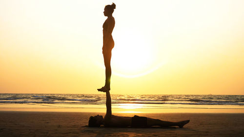 Silhouette people on beach against sky during sunset