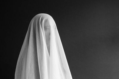 Close-up of woman in veil against gray background