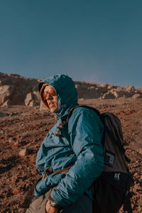 Man in warm clothing on land against clear sky