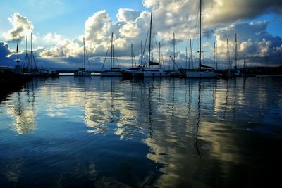 Sailboats moored in sea against sky