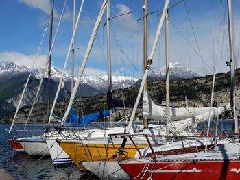 Sailboats moored in sea against sky