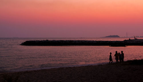 Silhouette people on beach against sky during sunset