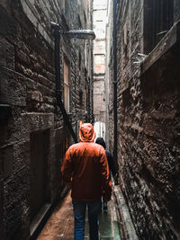 Rear view of man walking in narrow alley