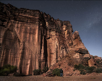 Low angle view of man standing against rock formation against