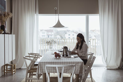 Businesswoman working at dining table in living room